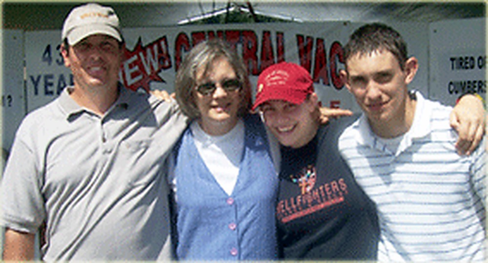 Four members of the O'Bryan family standing together at their trade show booth in front of a central vacuum banner