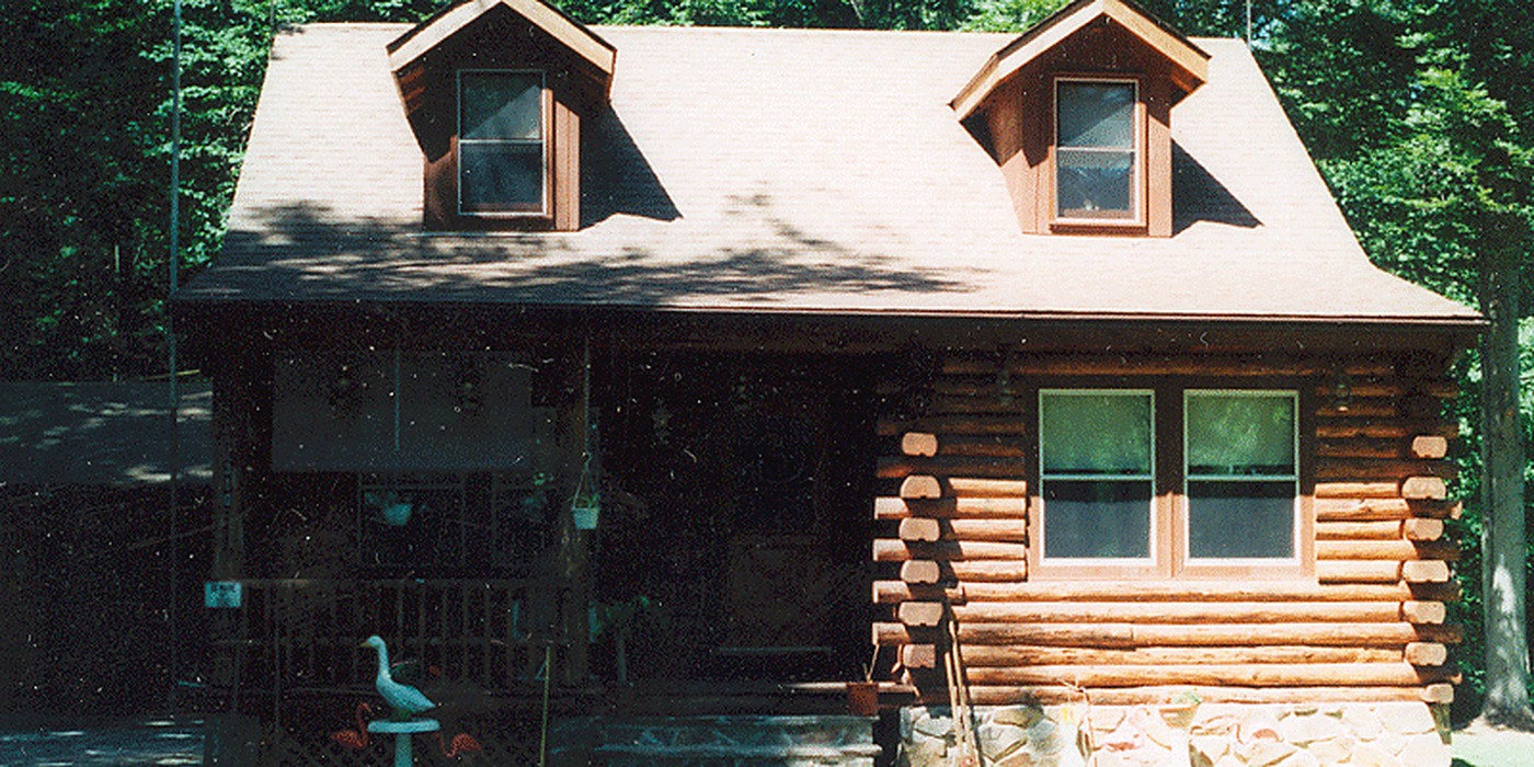 Log cabin home with dormer windows where A Plus Oaks installed a central vacuum through solid log walls