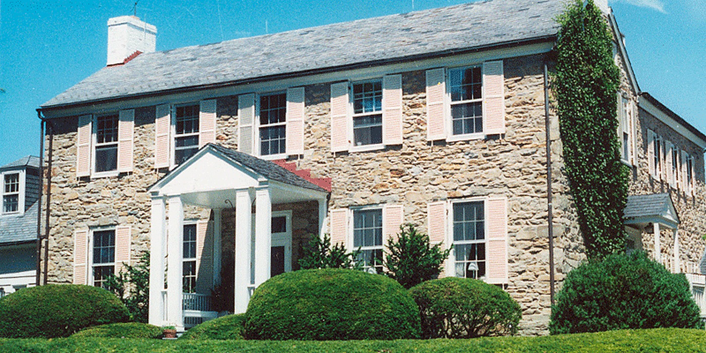 Historic Maryland stone colonial home with ivy and a white portico entrance where A Plus Oaks installed a central vacuum system